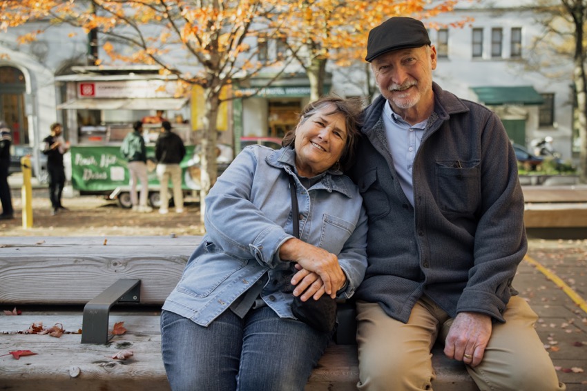 Older couple sitting on bench and smiling